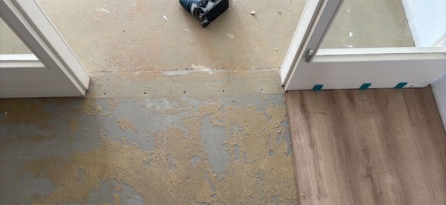 Übergang zwischen zwei Glastüren: links alter Untergrund, rechts neu verlegter Boden in Holzoptik