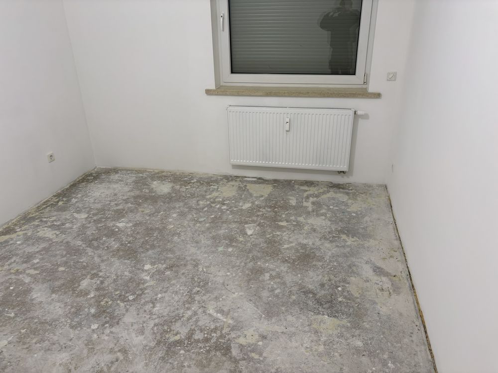 Leeres Zimmer mit frisch weißen Wänden, der alte Bodenbelag ist entfernt